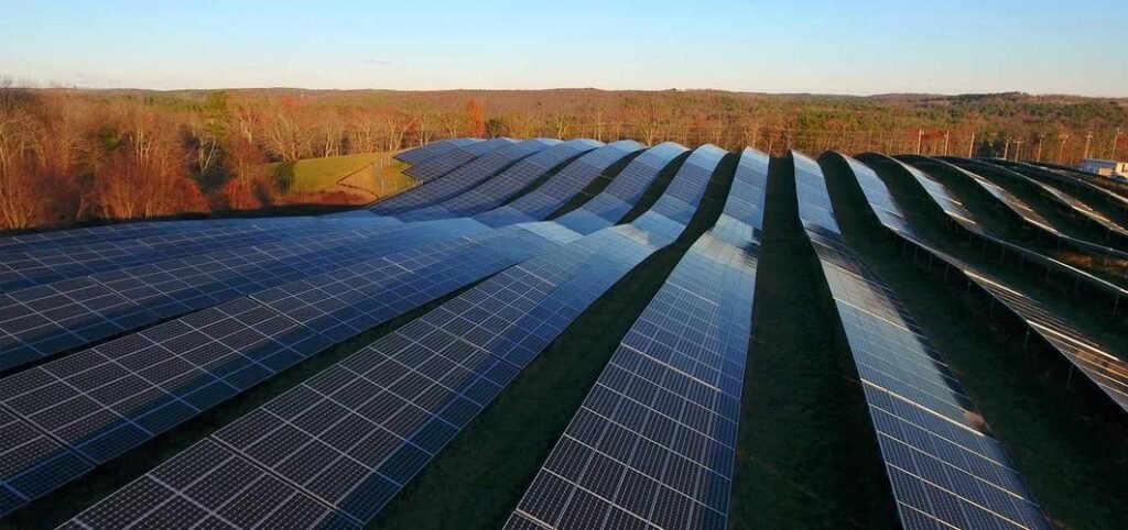 In this picture, situated on a mountain range amidst rolling hills, a ground-mounted photovoltaic support system is installed along the slope of the mountain. The surrounding woods have donned their autumn red, creating a stunningly beautiful landscape. The green energy generated by this system will further enhance the beauty of this magnificent natural scenery.